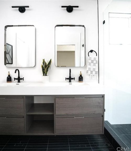  A modern bathroom vanity with a white countertop, grey wood cabinetry, and black fixtures.