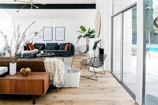 A stylish living room with a dark blue sofa adorned with orange pillows, and a mid-century modern wood coffee table.