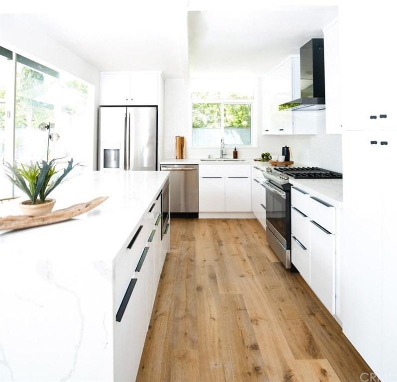 White kitchen with black accents, featuring a central island and modern appliances.