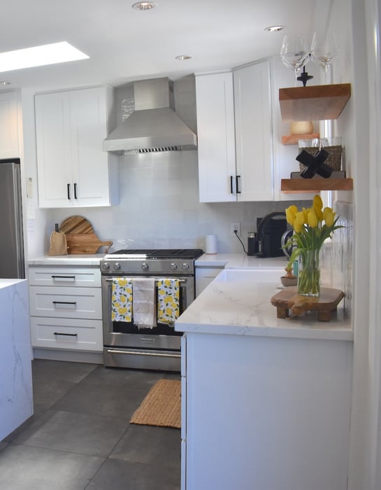 Kitchen with gray tile and white cabinets.