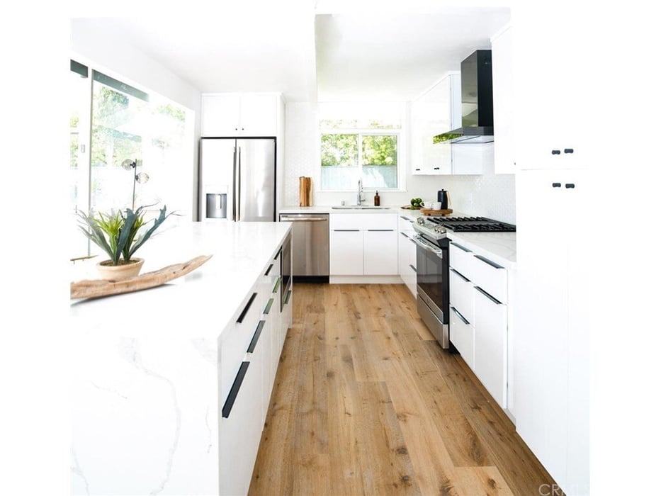  kitchen in Irvine, California with white cabinetry, stainless steel appliances, wood flooring, and large center island designed by an ADU builder in Orange County.