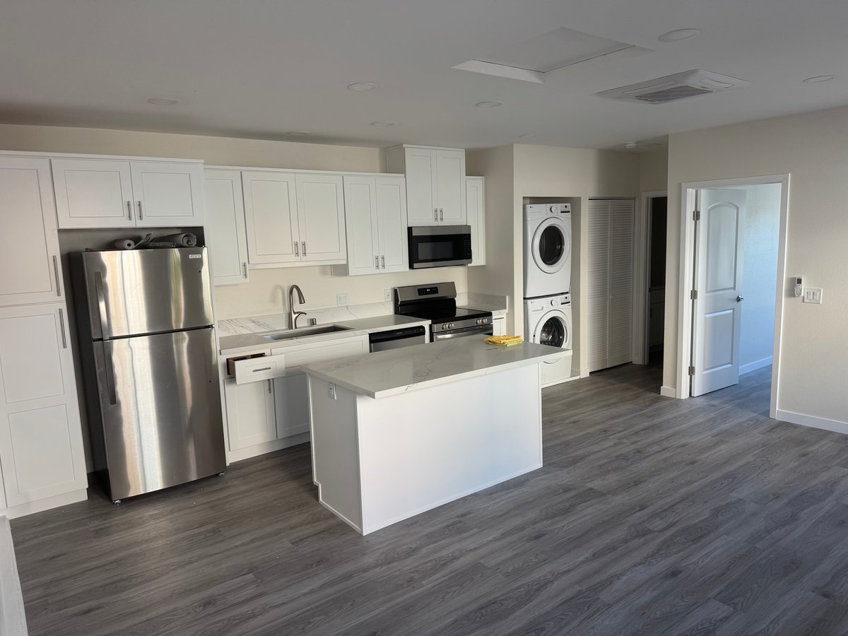 Finished ADU kitchen with white shaker cabinets, quartz countertops, stainless steel appliances, and large island