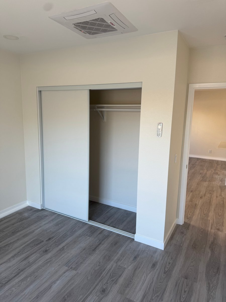 Finished ADU bedroom closet with sliding doors and vinyl plank flooring