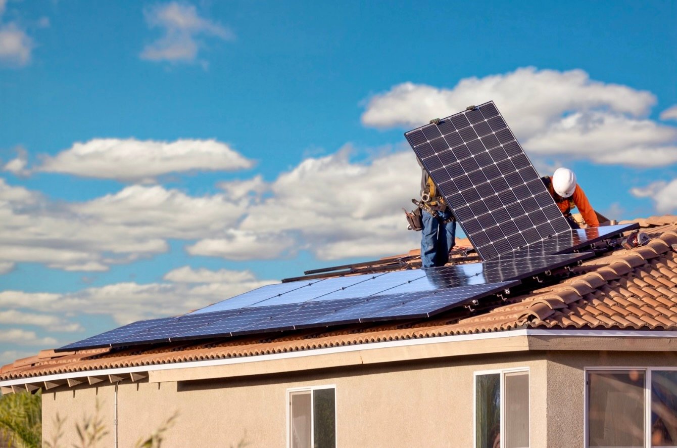 Solar installer placing panels on a tiled roof during residential solar installation