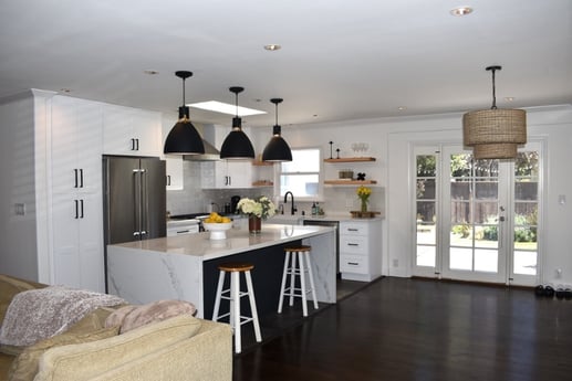  A bright and airy kitchen space with white cabinetry and a central island with a marble countertop.