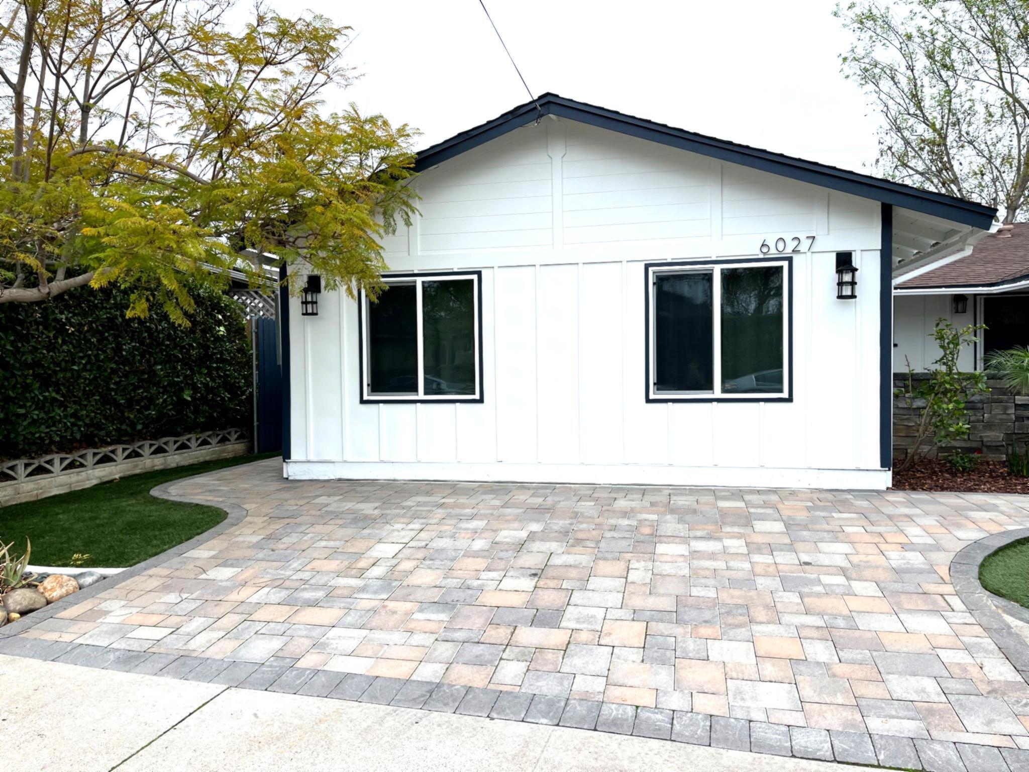 Exterior view of a converted garage ADU with white siding, black trim, and paved driveway in San Diego CA